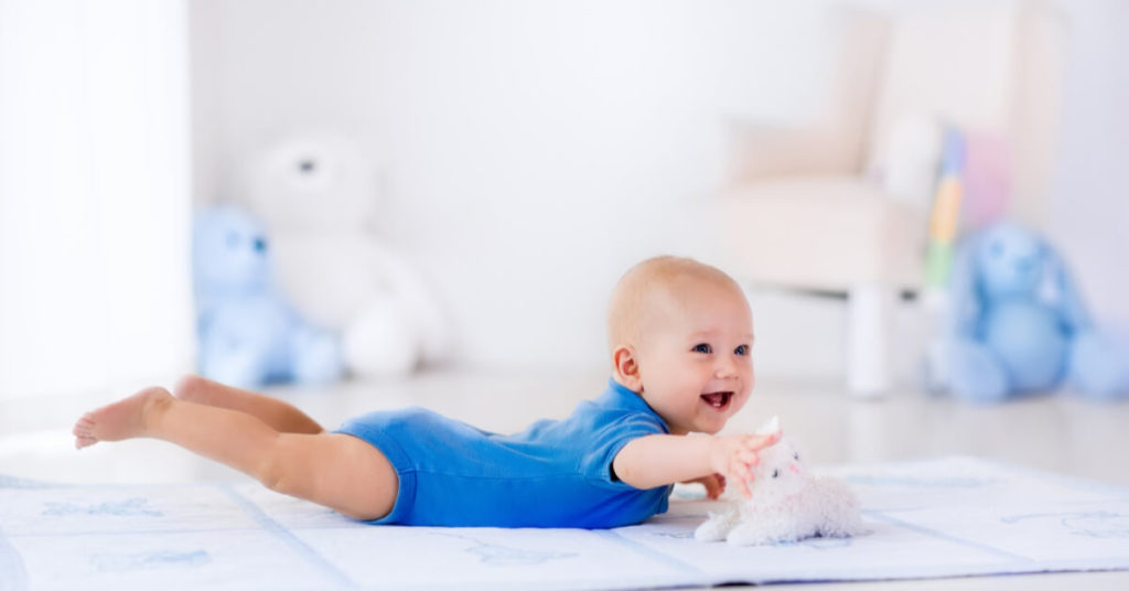 a baby lying on his stomach on a blanket | Teach Your Baby to Play Independently